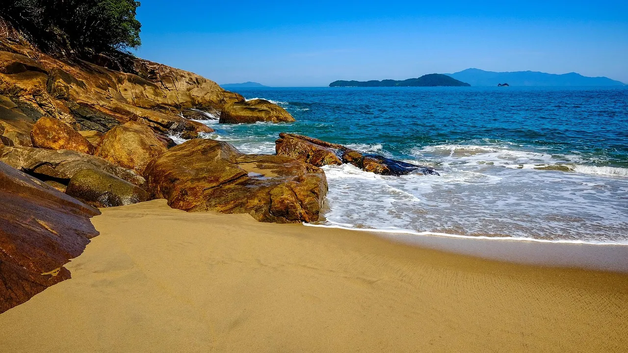 Praia tranquila em Ubatuba com faixa de areia e mata atlântica ao fundo